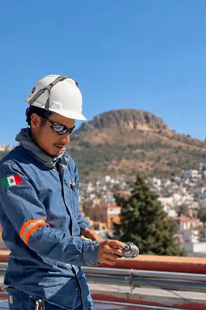 Instalador con casco y uniforme revisando su equipo en una azotea