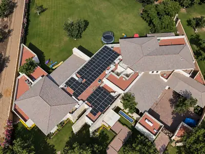 Casa con jardín vista desde el aire, con paneles solares en el techo
